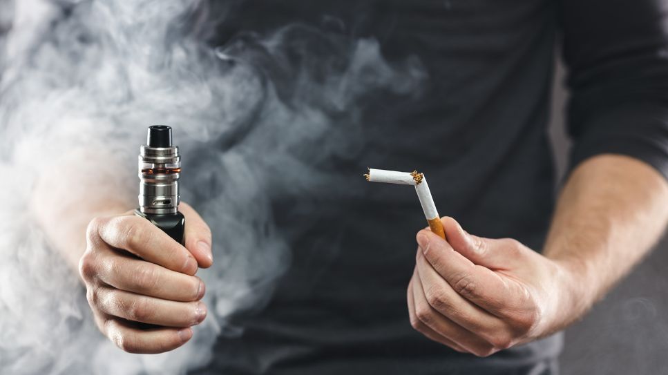 Hände halten E-Zigarette und geknickte Tabakzigarette (Bild: imago/Panthemedia)