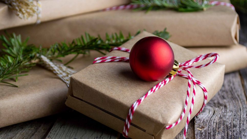 Weihnachtsgeschenke in Packpapier mit roter Kugel (Bild: unsplash/Mel Poole)