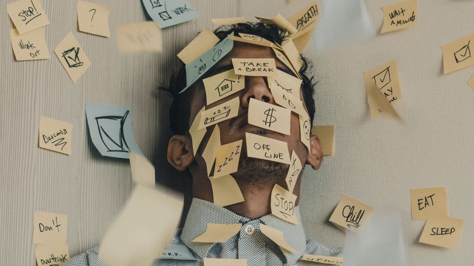 Mann mit Post-Its auf Kopf und Körper lehnt an Wandecke (Bild: unsplash/Luis Villasmil)