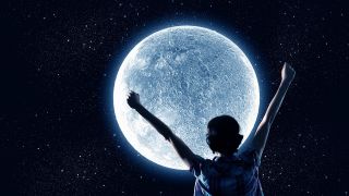 Frau mit erhobenen Armen steht vor Mond (Bild: imago/Shotshop)