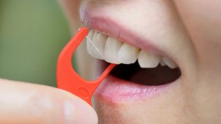 Frau reinigt Zähne mittels Zahnseide (Bild: imago/Shotshop)