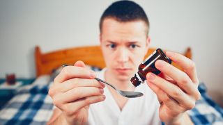 Mann tropft Arzneitropfen auf einen Löffel (Bild: imago/agefotostock)