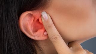 Frau hält sich das schmerzende Ohr (Quelle: imago/Panthermedia)