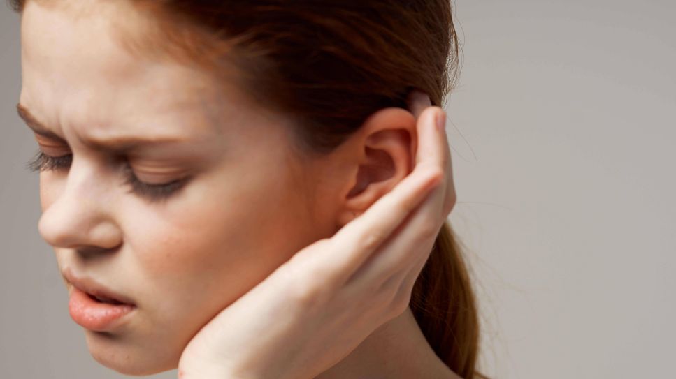 Frau mit schmerzverzerrtem Gesicht fasst sich ans Ohr (Bild: imago/YAY images)