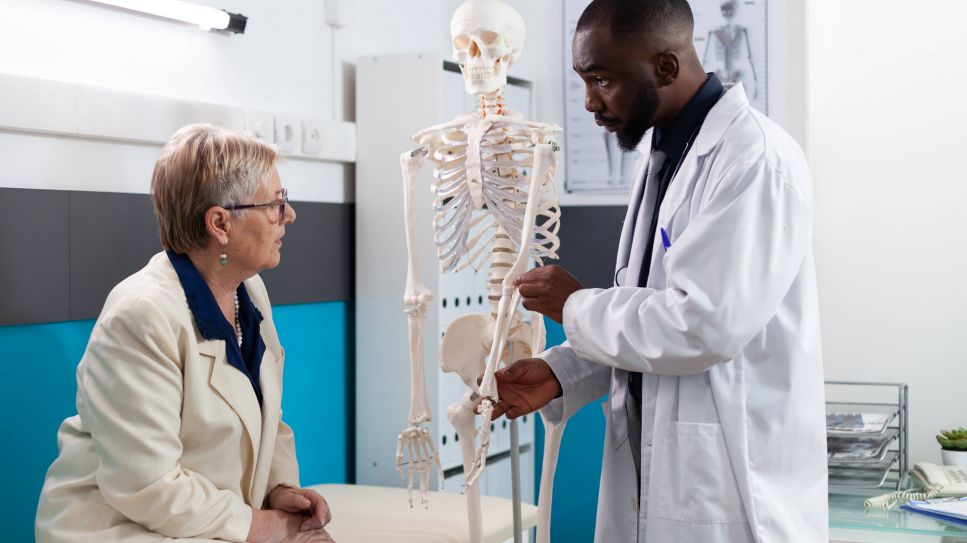 Arzt zeigt Patientin Knochen am Skelett (Quelle: imago/YAY Images)