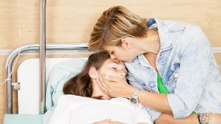 Mutter umarmt Kind im Krankenhausbett (Quelle: Colourbox)