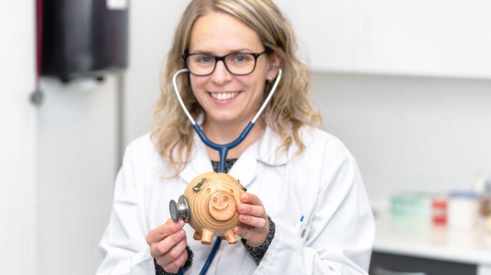 Ärztin hält Stethoskop am Sparschwein (Quelle: colourbox)