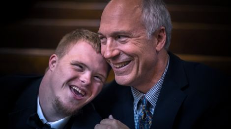 Arztbesuch mit geistiger Beeinträchtigung: Vater und Sohn mit Down Syndrom lachen (Bild: unsplash/Nathan Anderson)