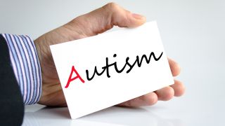 Mann in Anzug hält Schild mit Aufschrift: Autism (Quelle: Colourbox)