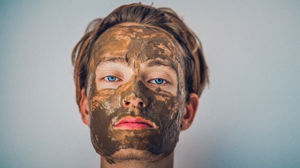 Heilmoor & Heilkreide: Schlammmaske auf Gesicht eines jungen Mannes (Bild: unsplash/Isabell Winter)