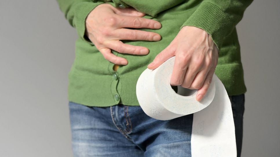 Morbus Crohn: Frau hält sich schmerzenden Bauch und dabei Toilettenpapier in der Hand (Bild: imago/Shotshop)