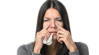 Nasennebenhöhlenentzündung: Frau mit Taschentuch reibt sich schmerzende Kieferhöhlen (Bild: imago/agefotostock)