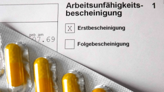 Krankschreibung: Pillen liegen auf Arbeitsunfähigkeitsbescheinigung (Bild: imago/Lobeca)