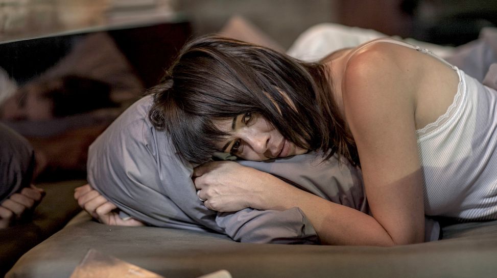 Schlafstörungen in den Wechseljahren: Frau liegt wach in Bett und umklammert Kissen (Bild: imago/Westend61)