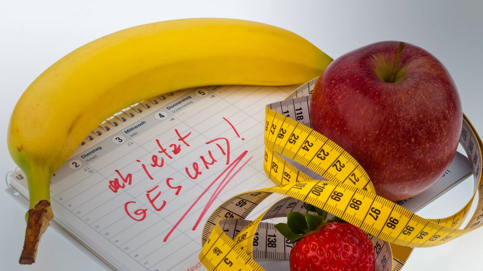 Gute Vorsätze: Bild zeigt Banane, Apfel, Maßband auf einem Kalender mit Aufschrift: "ab jetzt gesund!" (Quelle: imago images/ McPHOTO)