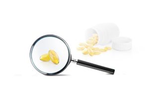Vitamin D - was können die Kapseln? - Bild zeigt aufgeschnittene Tablette, die mit Lupe vergrößert wird (Quelle: imago images / supachai sumrumsuk)