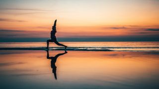 Yoga als Therapie: Bild zeigt Frau bei Yoga am Strand bei Sonnenuntergang (Bild: unsplash/Raimond Klavins)