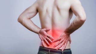 Rückenschmerzen: Bild zeigt Mann, der sich an schmerzenden unteren Rücken fasst (Bild: Colourbox)