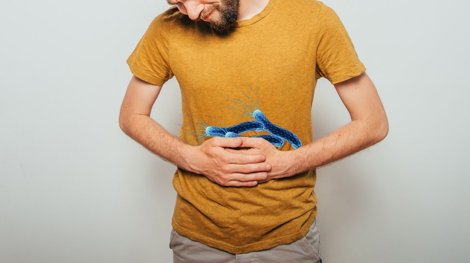 Magenschmerz durch Helicobacter: Bild zeigt Mann, der sich schmerzenden Bauch hält, darauf Bakteriengrafik (Bild: Colourbox)