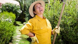 Rückenschmerz durch Gartenarbeit: Bild zeigt Frau im Garten, die sich unteren Rücken hält (Bild: imago images/shotshop)