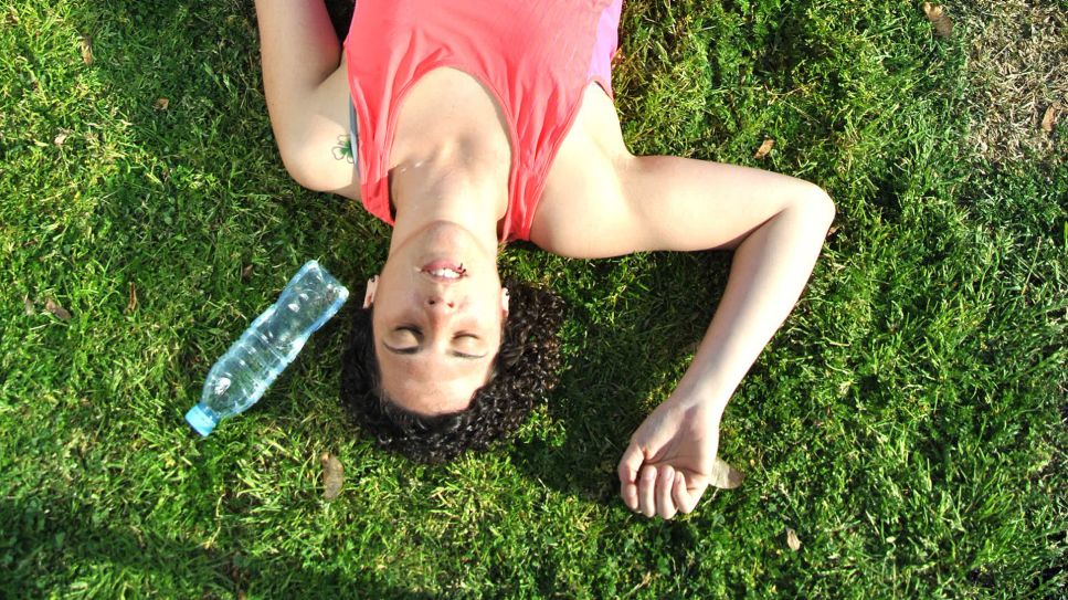 Kreislaufprobleme durch Hitze: Frau liegt erschöpft auf Grasfläche (Bild: Colourbox)