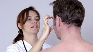 Fazialisparese, Bild zeigt Ärztin, die das Gesicht eines Patienten untersucht (Quelle: imago images / emil umdorf)