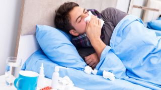 Grippe (Influenza): Mann mit Grippe liegt neben Medikamenten und Taschentüchern im Bett (Bild: Colourbox)