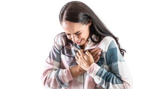 Plötzlicher Herztod: Junge Frau hält sich Hände an schmerzende Brust (Bild: Colourbox)