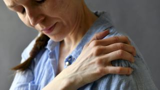 Gelenkschmerzen in Wechseljahren: Bild zeigt Frau, die sich schmerzende Schulter hält (Bild: imago images/Lehtikuva)
