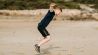 Mann springt auf Sandfläche mit ausgestreckten Armen (Bild: unsplash/ Annie Spratt)