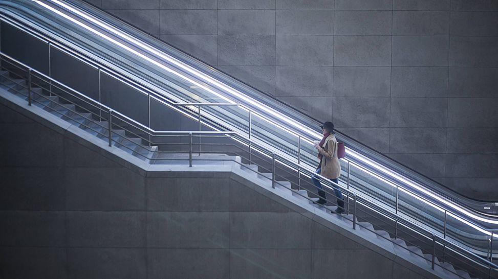 Frau geht eine Treppe statt der daneben liegenden Rolltreppe hinauf (Quelle: imago/Westend61)