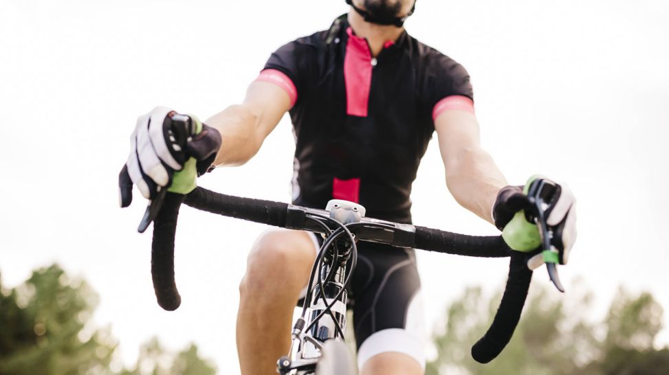 Mann fährt mit Rennrad, Fokus ist auf dem Lenkrad, Arme sind leicht gebeugt (Quelle: imago/Westend61)