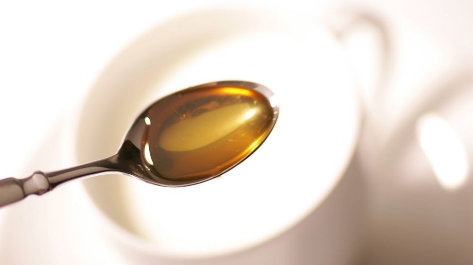 Heiße Milch in einer Tasse und ein Löffel mit Honig (Quelle: imago/Frank Müller)