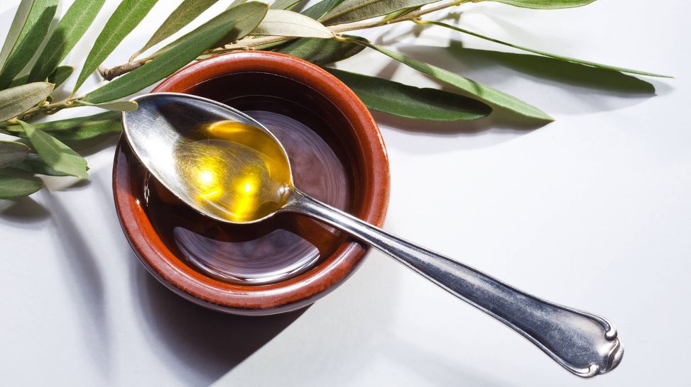 Cholesterin senken: Olivenöl neben Zweig auf einem Löffel (Bild: imago/Shotshop)