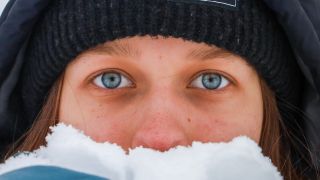 Augen einer frau mit Mütze gucken über Schnee in Hand (Bild: unsplash/Hans Isaacson)