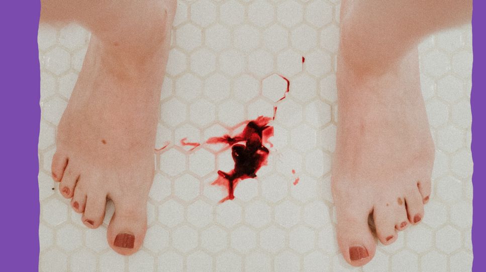 Nackte Füße stehen auf Fliesen, dazwischen ein Blutfleck (Bild: unsplash/Monika Kozub)