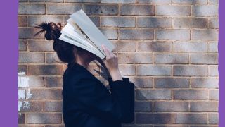 Junge Frau hält sich ein Buch über dem Kopf (Quelle: siora/unsplash)