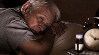 Mann liegt schlaflos im Bett und starrt auf Wecker (Bild: Colourbox)