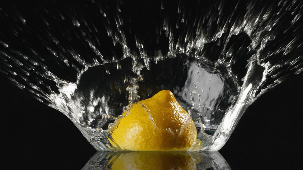 Eine Zitronenhälfte fällt ins Wasser