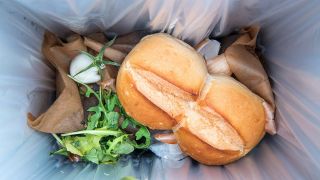 Nahaufnahme von einem Brötchen und anderen Lebensmitteln in einem Mülleimer (Quelle: imago images/Mario Hösel)