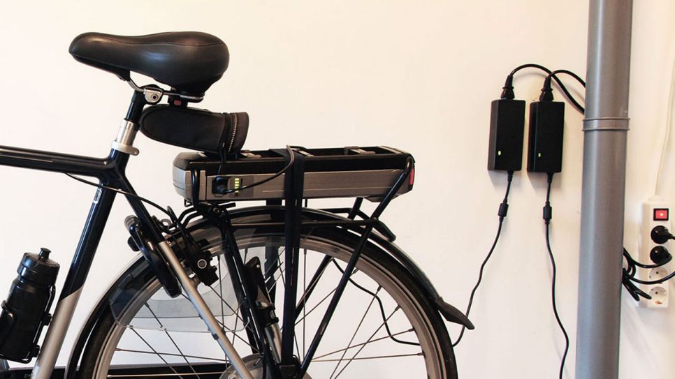 Der Akku eines E-Bikes wird an einer Steckdose in einer Garage aufgeladen (Quelle: Colourbox)