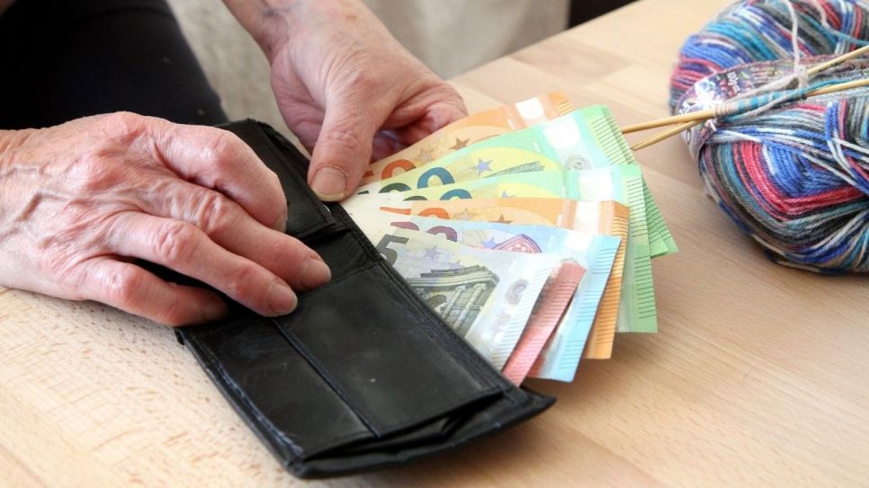 Zwei ältere Hände, ein Portemonnaie und ein Wollknäeuel. (Quelle: picture alliance / Eibner-Pressefoto | Fleig / Eibner-Pressefoto)