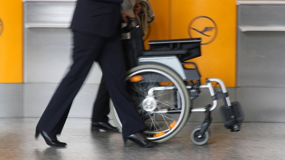 Lufthansa-Mitarbeiterin schiebt Rollstuhl (Quelle: IMAGO / Ralph Peters)