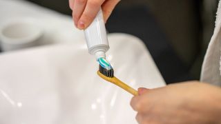 Person macht Zahnpasta auf eine Zahnbürste (Quelle: IMAGO / Westend61)