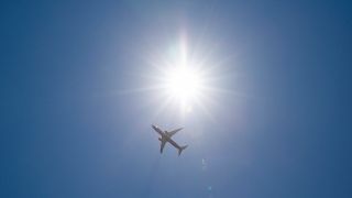 Flugzeug am Himmel vor strahlender Sonne (Quelle: IMAGO / Kirchner-Media)