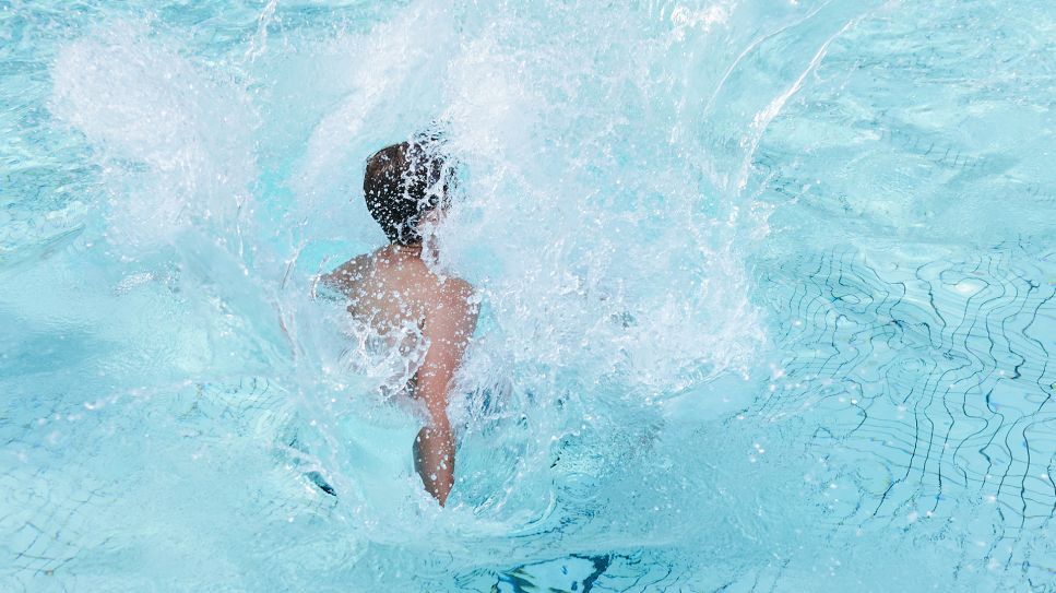 Ein Kind springt ins Schwimmbecken im Sommerbad Olympiastadion.Quelle: dpa/ Annette Riedl