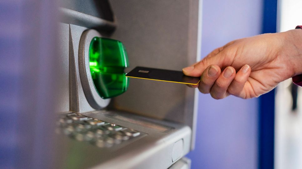 Person steckt Bankkarte in einen Automaten (Quelle: IMAGO / Westend61)