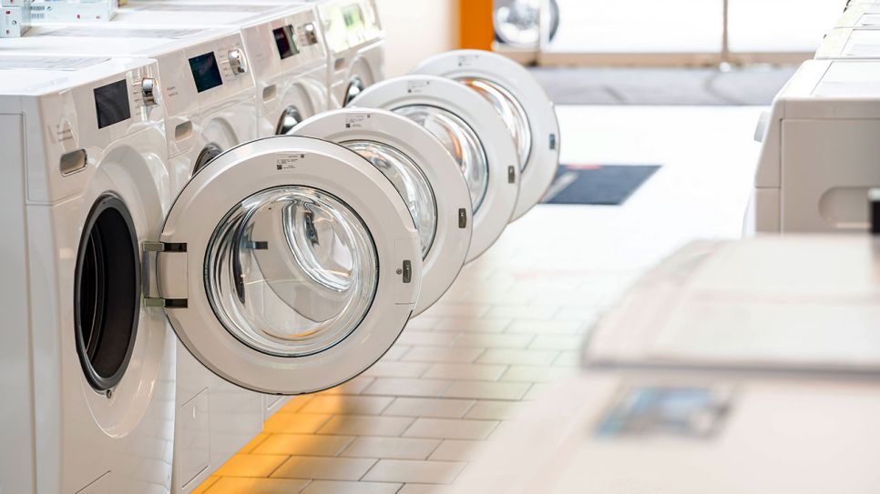 Mehrere geöffnete Waschmaschinen in einer Reihe (Quelle: IMAGO / Bihlmayerfotografie)