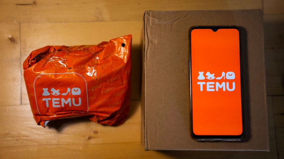 Ein Temu-Paket neben dem Smartphone, auf dem das Logo zu sehen ist (Quelle: imago images/NurPhoto)