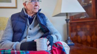 Älterer Herr mit handschuhen auf dem Sofa (Quelle: imago images/ingimages)